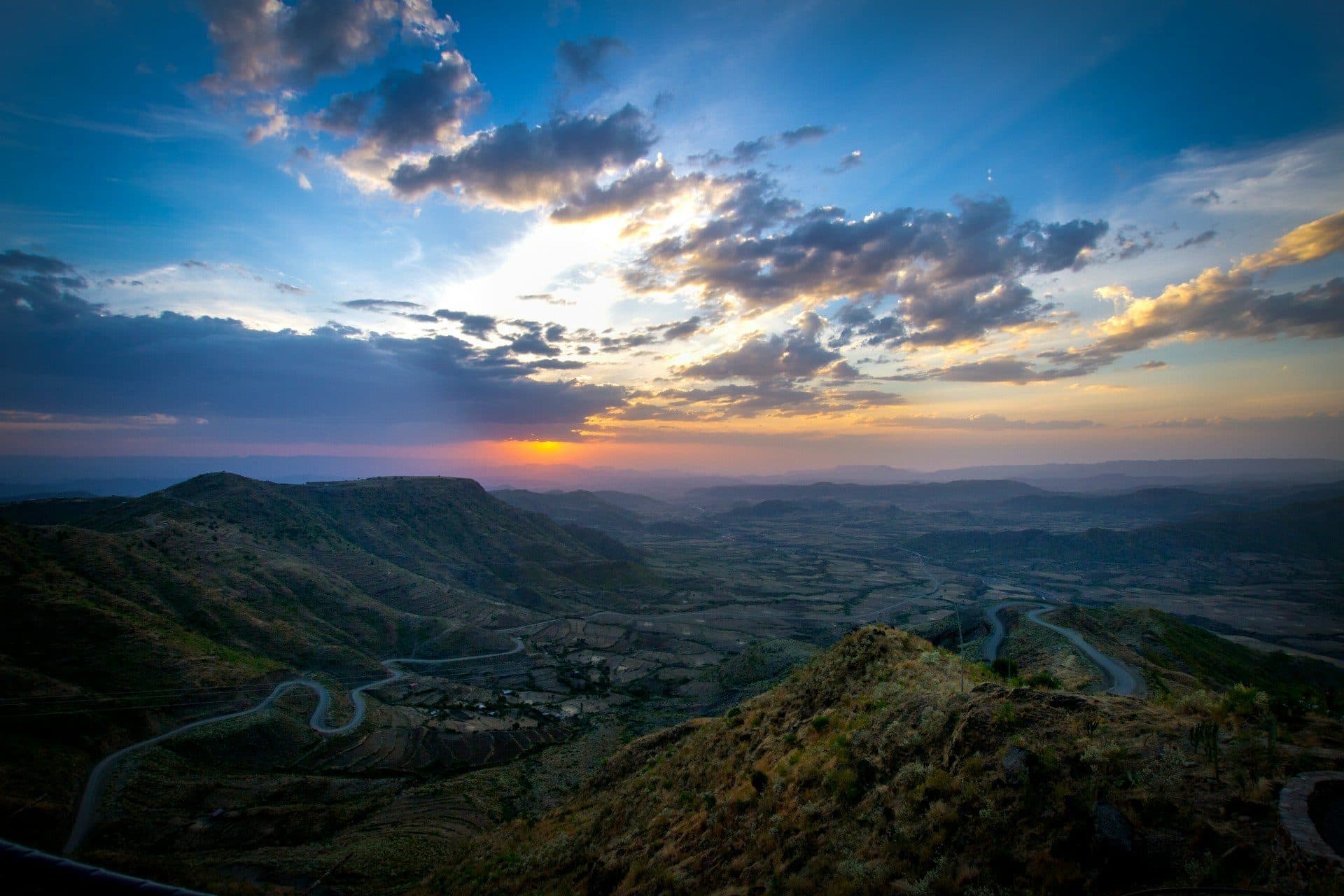 The serrated escarpment of the Simien Mountains at dawn with gelada baboons on the cliff edge and the high plateau falling away into cloud