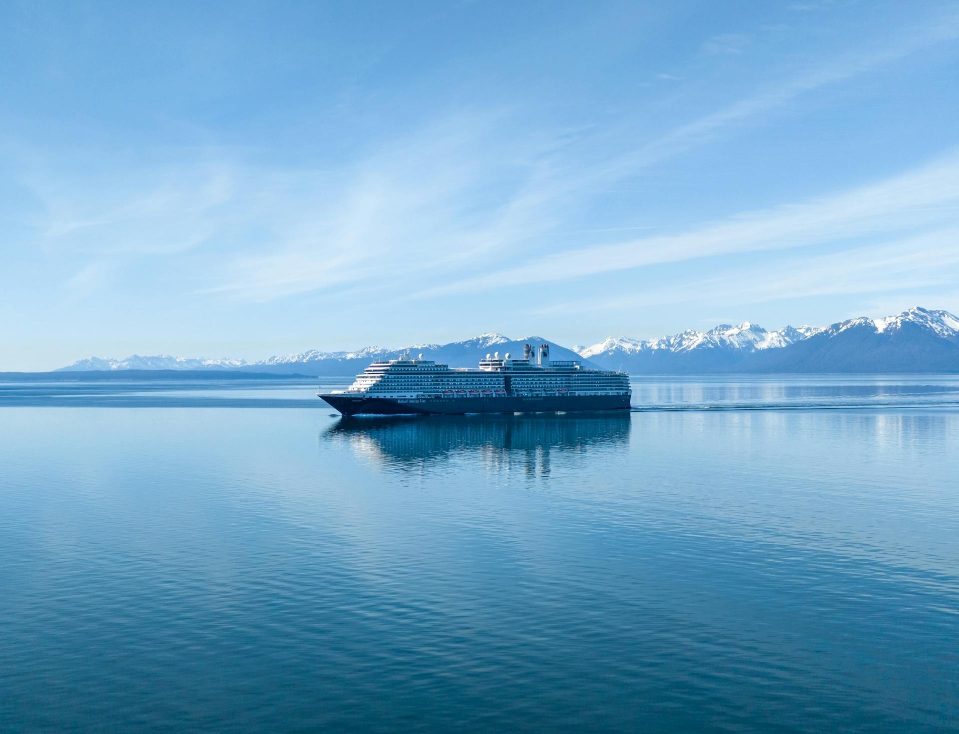 A large cruise ship sailing past a tidewater glacier in southeast Alaska under low cloud