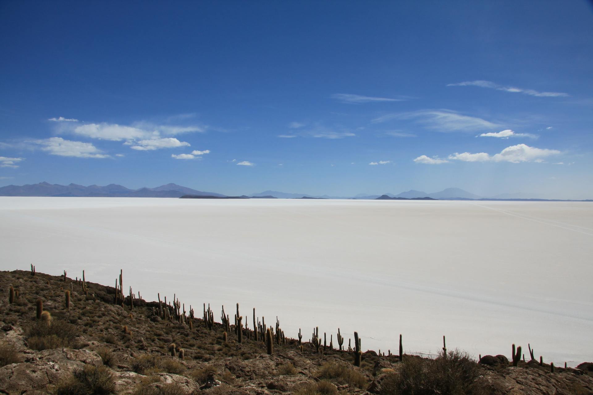 The Salar de Uyuni salt flats at sunrise reflecting a thin layer of water with distant Andean peaks on the horizon