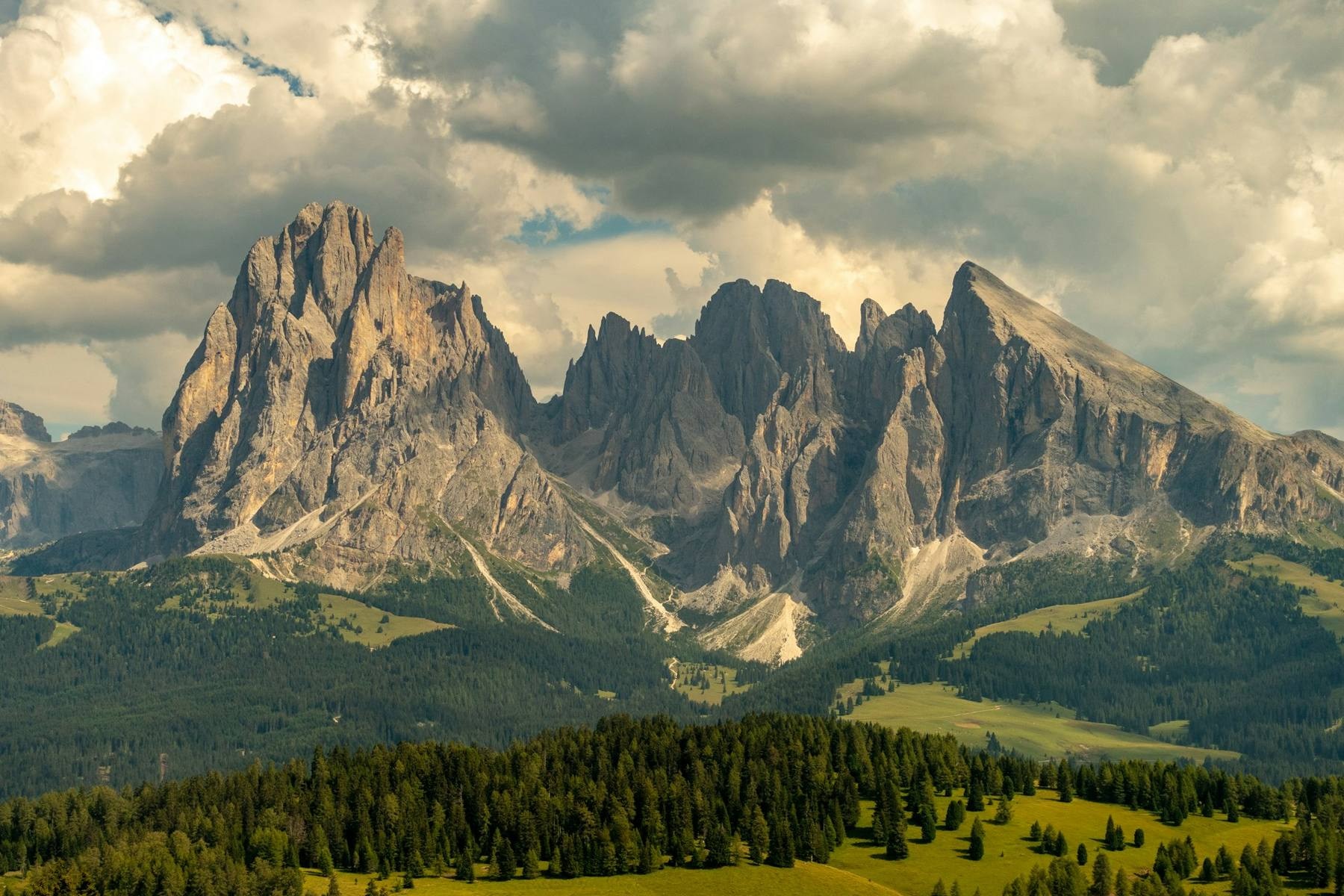 Trekkers on a Dolomites ridgeline above a rifugio with the Tofane and Cinque Torri spires in the background, late afternoon alpine light