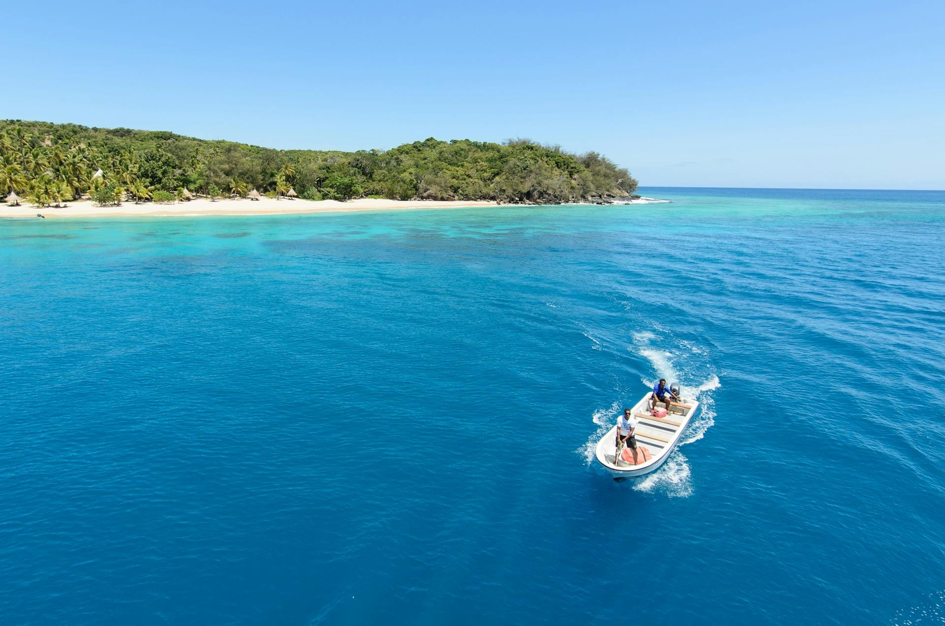 A high-speed catamaran ferry crossing turquoise water with a forested Yasawa island in the background